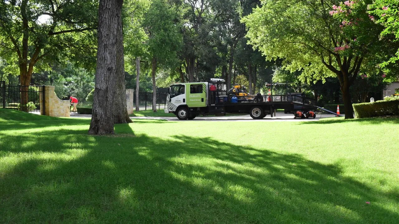 Large service truck in the distance with workers cutting grass