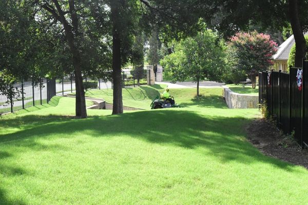 Blade Runner employee cutting lush green lawn on a riding lawnmower